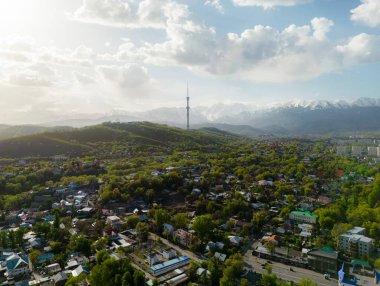 Güneşli bir bahar günü, arka planda karlı dağlarla birlikte televizyon kulesiyle Almaty şehrinin havadan görünüşü