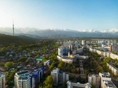 Güneşli bir bahar günü, arka planda karlı dağlarla birlikte televizyon kulesiyle Almaty şehrinin havadan görünüşü