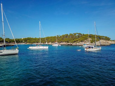 İspanya 'nın Mallorca Adası' ndaki Cala Llombards (Santanyi) plaj koyunda güneşli yaz günlerinde yüzen teknelerin hava görüntüsü