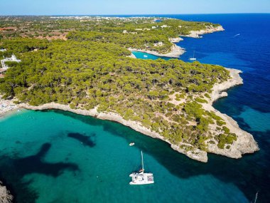 Aerial view of floating boats in Cala Llombards (Santanyi) beach bay in Mallorca Island in Spain during summer sunny day clipart