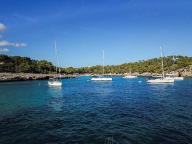 Aerial view of floating boats in Cala Llombards (Santanyi) beach bay in Mallorca Island in Spain during summer sunny day clipart