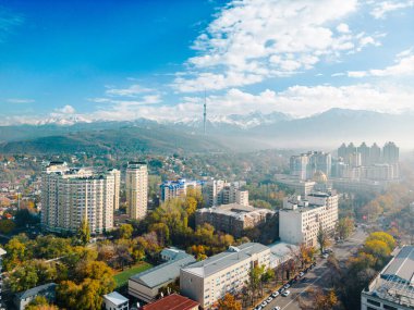 Güneşli bir günde kar tepeli dağlarla birlikte Almatı şehrinin televizyon kulesiyle hava görüntüsü