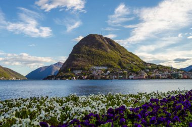 Lugano Gölü ve tepe manzaralı çiçekler. Lugano Gölü, İsviçre 'nin güneyiyle İtalya' nın kuzeyinde yer alan bir buzul gölüdür..