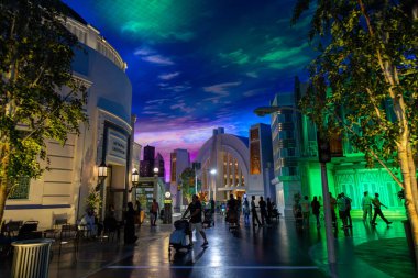 Abu Dabi, BAE - 24 Nisan 2024: Abu Dabi 'deki Warner Bros Dünyası' nın manzarası, temalı binalar, tabelalar ve akşamdan keyif alan ziyaretçilerin bulunduğu canlı, aydınlık bir cadde sergiliyor