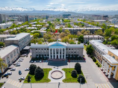 Arka planda karlı dağlar olan Bishkek Belediye Binası 'nın hava manzarası