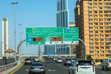 Dubai, Birleşik Arap Emirlikleri - 21 Haziran 2023: Bir gün boyunca Dubai otoyolunda arabalar ve gökdelenlerle yol tabelası