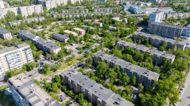 Sovyet döneminde inşa edilmiş, yeşillik ve daha küçük yapılarla çevrili Bishkek 'teki çok katlı binaların hava manzarası..