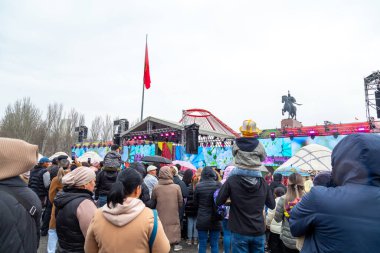 Bişkek, Kırgızistan - 21 Mart 2024: Kırgızistan 'ın merkez meydanında Nowruz kutlamaları sırasında Kırgız Türkiyesi' nin yüksek başlıklı şapkasını takan baba kucağında