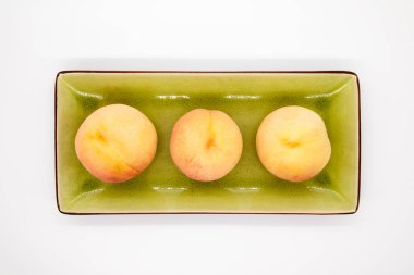 Olgun organik şeftaliler yeşil tabakta beyaz arka planda