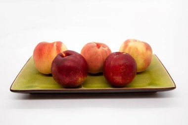 Olgun organik şeftaliler yeşil tabakta beyaz arka planda