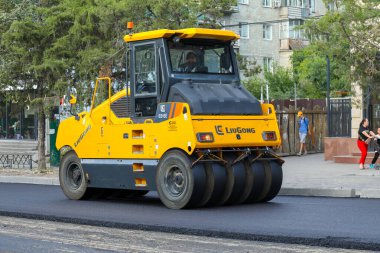 Bişkek, Kırgızistan - 14 Ağustos 2024: Sarı asfalt silindirli yol yapımı