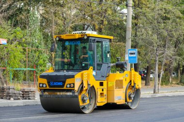 Bişkek, Kırgızistan - 14 Ağustos 2024: Yol yapımı sırasında yeni bir asfalt tabakasını düzleştiren bir yol paten makinesi, makine ve sokak ortamına odaklı