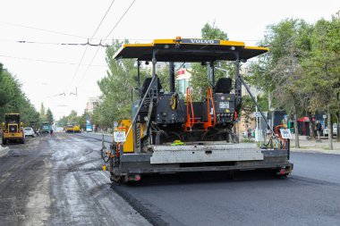 Bişkek, Kırgızistan - 22 Ağustos 2024: Bir şehir caddesinde yol yapımı sırasında faaliyet gösteren bir Volvo P7820D ABG asfalt kaldırım geçidi, ekipmanın altyapı geliştirmedeki rolünü vurguluyor