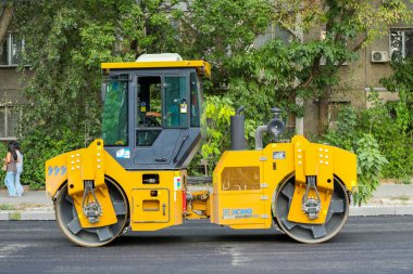 Bişkek, Kırgızistan - 14 Ağustos 2024: Bişkek 'te yol yapımı sırasında yeni bir asfalt tabakasını düzleştiren bir yol paten makinesi, özellikle de makine ve sokak ortamını hedef alıyor