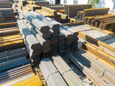 Galvanize demir borular ve paslanmaz çelik dikdörtgen metal çubuklar arka planda gantry vinç ile
