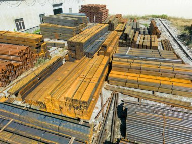 Galvanize demir borular ve paslanmaz çelik dikdörtgen metal çubuklar arka planda gantry vinç ile