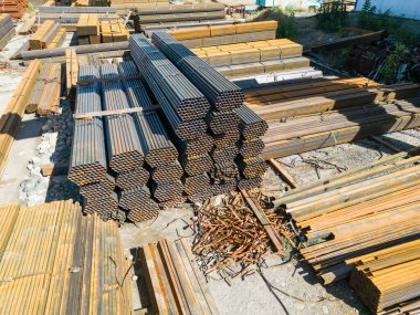 Galvanize demir borular ve paslanmaz çelik dikdörtgen metal çubuklar arka planda gantry vinç ile
