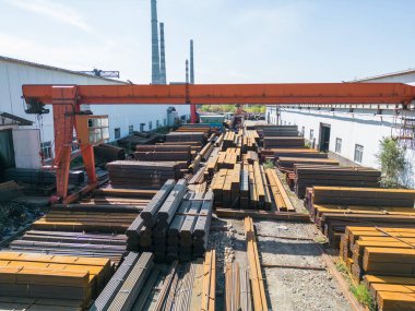 Galvanize demir borular ve paslanmaz çelik dikdörtgen metal çubuklar arka planda gantry vinç ile