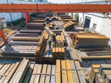 Çelik fabrikasında metal borular taşıyan işçilerin hava görüntüsü.