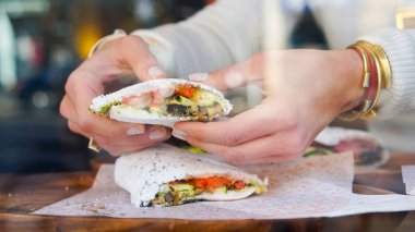 Tapioca un sandviçi ellerinde.