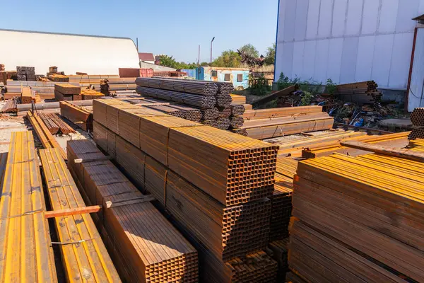 Galvanize demir borular ve paslanmaz çelik dikdörtgen metal çubuklar arka planda gantry vinç ile