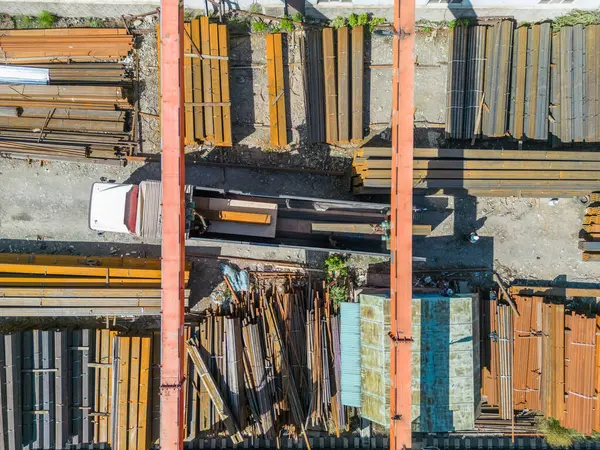 Metal boruları gantry vinçle yükleyen işçilerin havadan aşağı görüntüsü