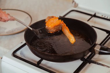 Ev mutfağında cızırdayan yağlı tavadan kızarmış somon balığı çıkarıyorum.