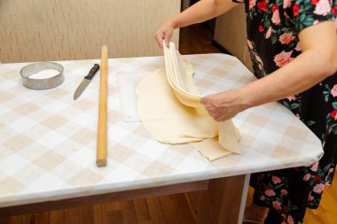 Masaya raptiye takmış hamuru yuvarlayan bir kadın.