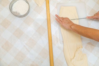 Masada bıçakla hamuru dilimleyen bir kadın.