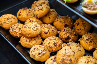 Üzerine fındık ve tohum konmuş lezzetli puf seçimleri, bir etkinlikte kolay servis edilmesi için siyah bir tepside dizilmiştir.