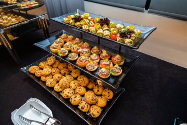 Büyük ölçekli bir etkinliğe hazırlanan aperatiflerden tatlılara kadar bir dizi yiyecek seçeneğinin sunulduğu geniş bir catering düzeninin tam görünümü