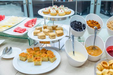 Şık yemeklerde sunulan çeşitli tatlıların, taze meyvelerin ve fındıkların yer aldığı müsrif bir büfe.