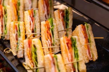 Çeşitli dolgularla klasik sandviç üçgenleri. Siyah bir yemek tepsisine yerleştirilmiş. Etkinlik yemeği için mükemmel.