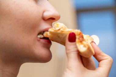 Diş teli takmış pizza yiyen bir kadın.