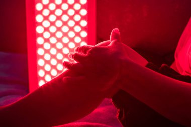 Closeup of sore leg of a person treating with the red light therapy panel clipart