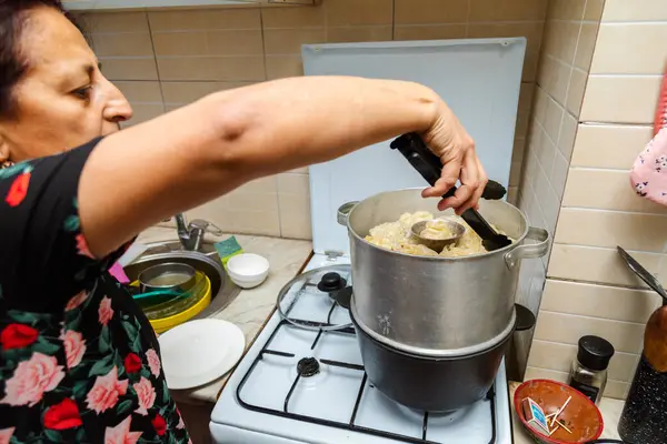 Kadın ocakta maşayla manti (hamur köftesi) pişirmeye hazır olup olmadığını kontrol ediyor.