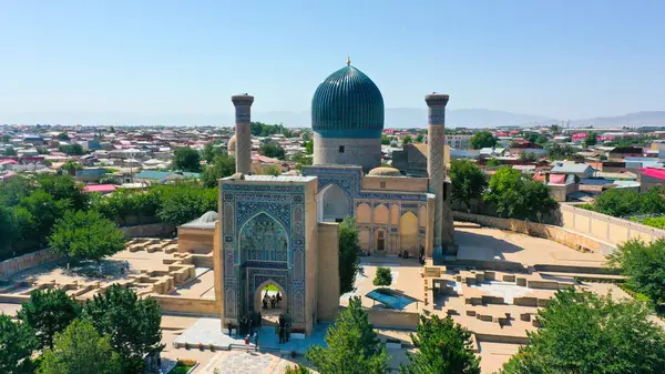 stock image Samarkand, Uzbekistan - July 15, 2024: Aerial view of the historic Amir Temur Mausoleum Gur-i Amir Complex with its blue dome, surrounded by the cityscape and mountains