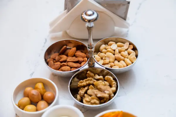 stock image Variety of healthy snacks including nuts, chips, and dips neatly arranged in white bowls on a marble table