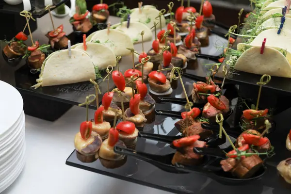 Detaylı taco ve şiş aperatifleri bir catering etkinliğinde siyah bir tepsiye dizilmiş, taze malzemeler ve sunum vurgulanıyor