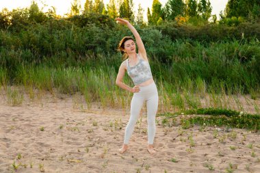 Dışarıda egzersiz yapan, antrenmandan önce ısınan formda bir kadın. Kollarını uzat ve uzaklara bak.