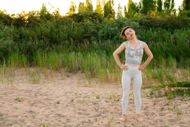 Dışarıda egzersiz yapan, antrenmandan önce ısınan formda bir kadın. Kollarını uzat ve uzaklara bak.