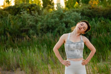 Dışarıda egzersiz yapan, antrenmandan önce ısınan formda bir kadın. Arkanı dön ve gözlerini kapat.