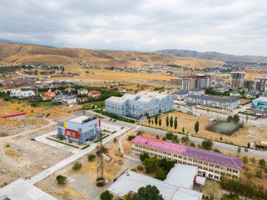 Bishkek, Kyrgyzstan - August 31, 2024: Aerial view of the American University of Central Asia campus, including the Makerspace Learning and Design Center, set against a mountainous backdrop clipart