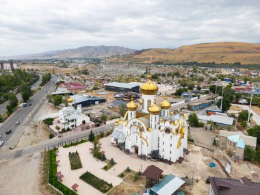 Bişkek, Kırgızistan - 31 Ağustos 2024: Kutsal Havarilere Eşit Ortodoks Kilisesi 'nin havadan görünüşü, altın kubbeleri ve çevresini gösteren Büyük Dük Vladimir