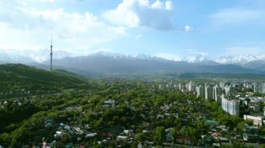 Güneşli bir bahar günü, arka planda karlı dağlarla birlikte televizyon kulesiyle Almaty şehrinin havadan görünüşü