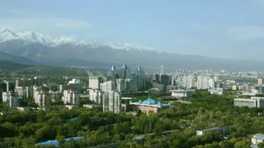 Güneşli bahar gününde, arka planda karla kaplı dağlarla Almaty şehrinin hava manzarası.