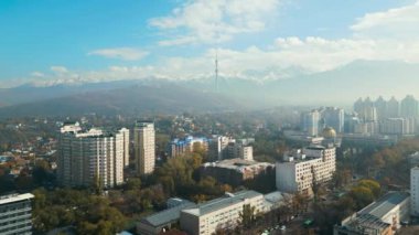 Güneşli bir günde kar tepeli dağlarla birlikte Almatı şehrinin televizyon kulesiyle hava görüntüsü