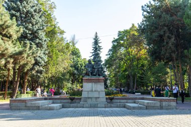 Bishkek, Kırgızistan - 31 Ağustos 2024: Karl Marx 'ın bir anıtı, bir filozof ve sosyalist, ve Friedrich Engels, bir siyasi kuramcı, ağaçlarla çevrili bir parkta, yürüyen insanlar
