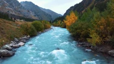 Kazakistan 'da yeşil ağaçlar ve dağlarla çevrili Kora nehrinin havadan görünüşü