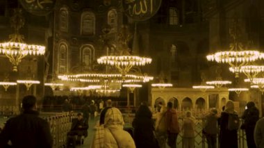 İstanbul, Türkiye - 21 Ekim 2022: Altın ışıklı Ayasofya içinde ziyaretçi ve ibadet edenlerin yavaş hareketi, tarihi ihtişamını gözler önüne seriyor.